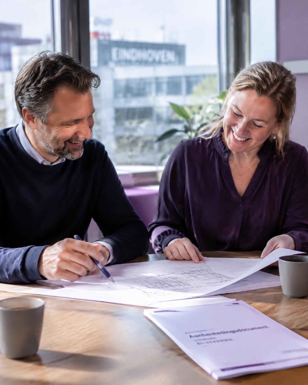 Twee adviseurs van Stipt bespreken tekeningen aan tafel